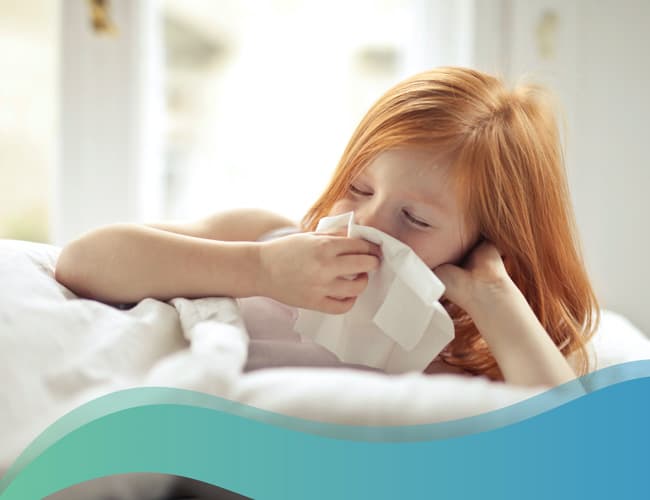 Sick red haired girl is blowing her nose