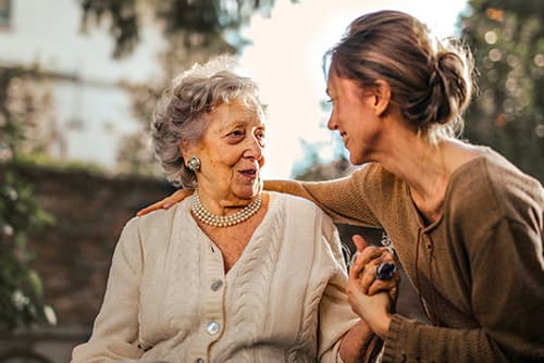 A women puts her arm around an older woman.