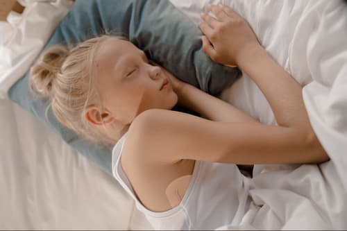 A young, blonde girl is asleep in bed, a STEADYTEMP® patch is visible under her arm.